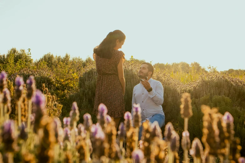 man looking at woman in field with purple flowers