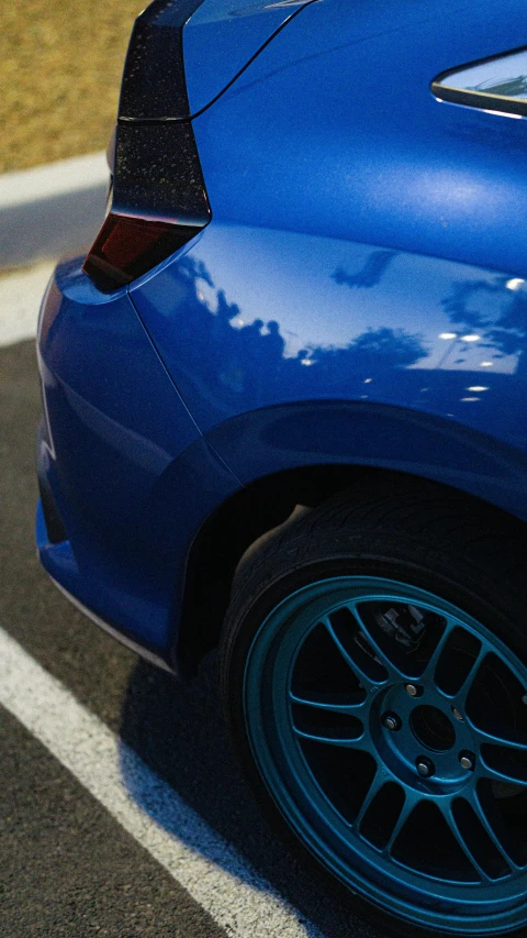 the back view of a blue car parked in a parking lot