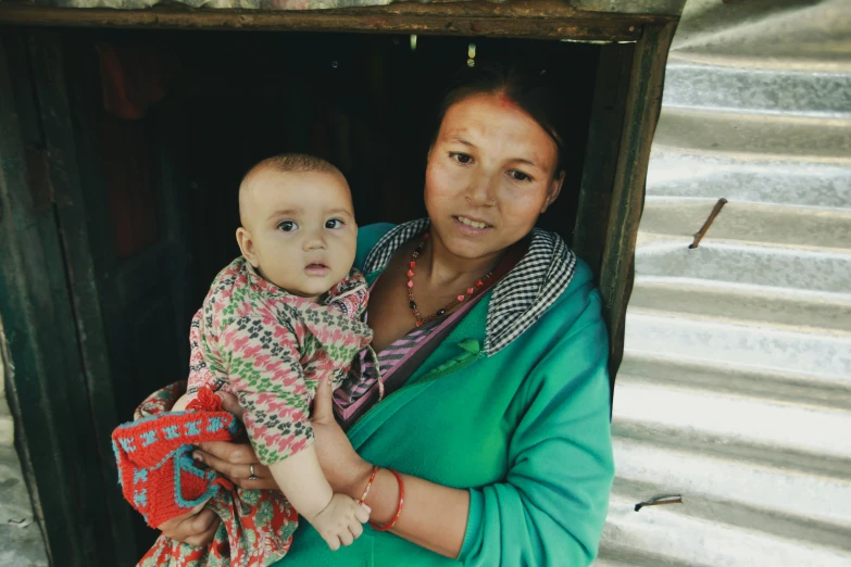 a woman holding a baby in a green top