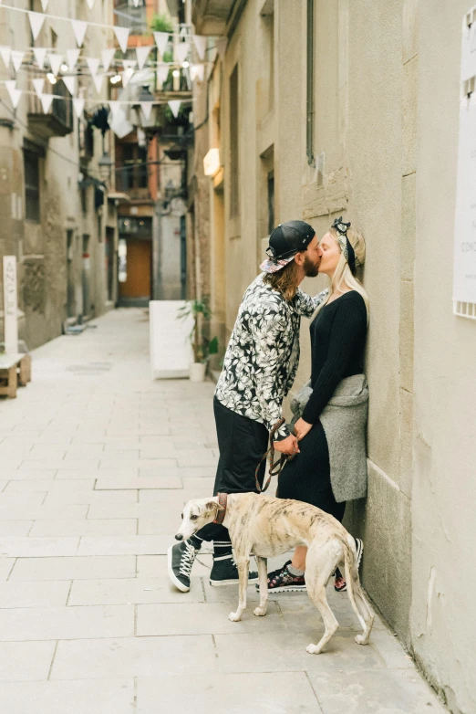 a couple kissing on the street with their dogs