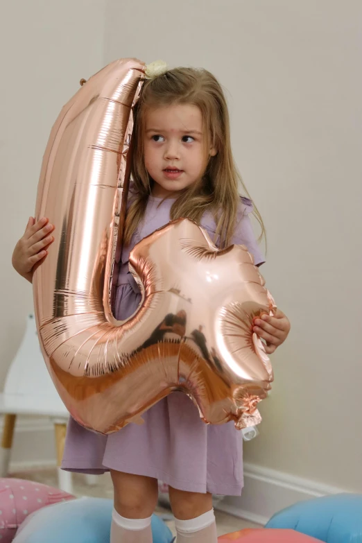 a small girl is holding onto a large metal letter j