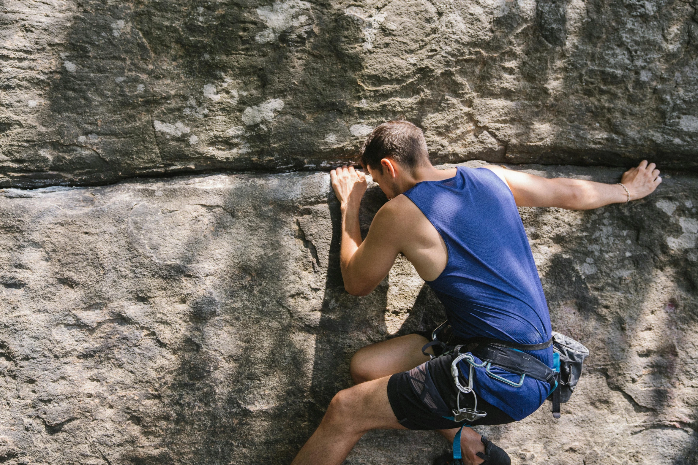 a man climbing up a stone wall on a cell phone