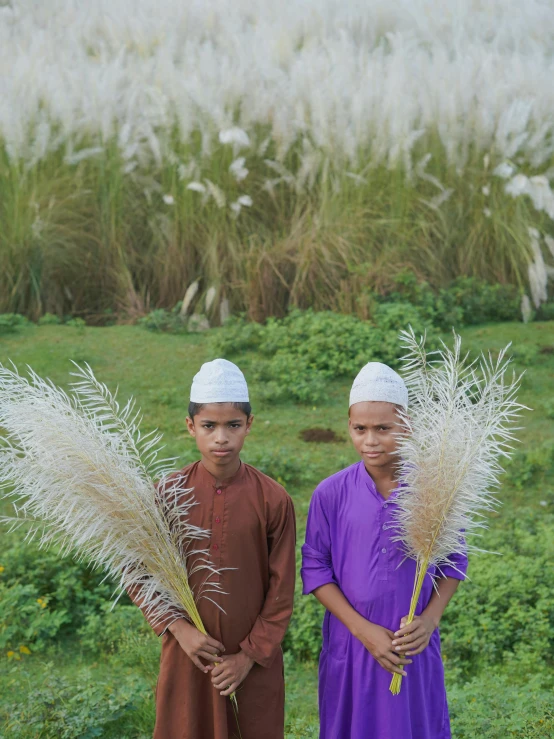 two children are standing beside each other holding some plants