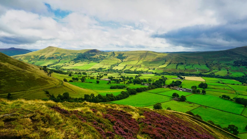 a valley and mountains with green grass below and overcast sky