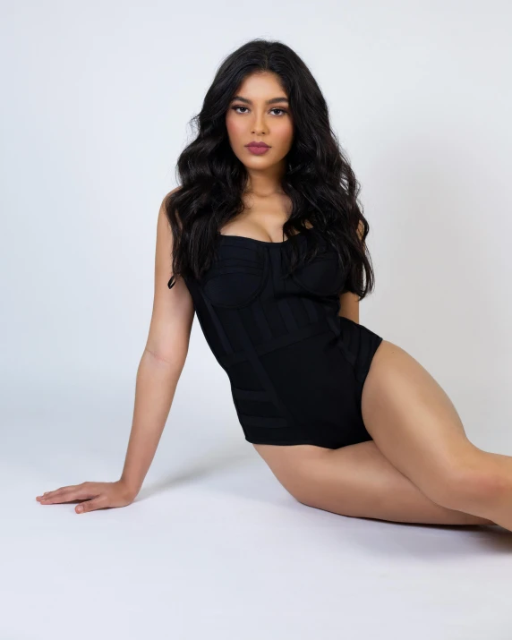 a women in a black bathing suit posing on the floor