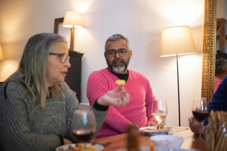 two people holding a wine glass, sitting at a table