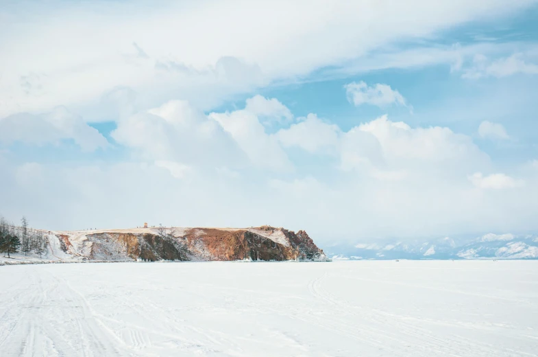 a snow covered field with two hills on the right and one mountain off in the middle