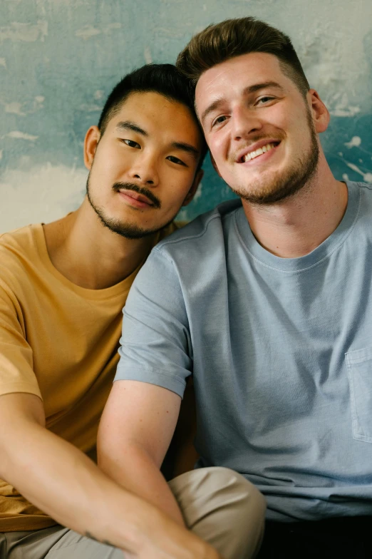 two men posing together with a wall behind them