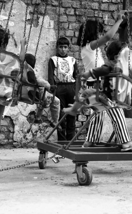 children sit in swing chairs at the park