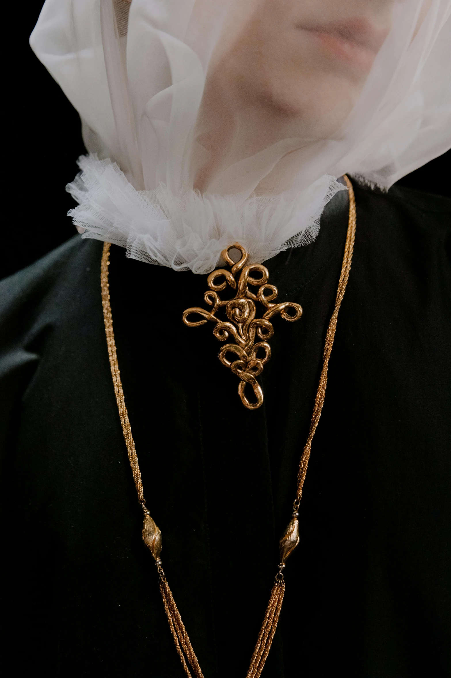 the white - haired person with a veil covers her face and wears large gold necklaces