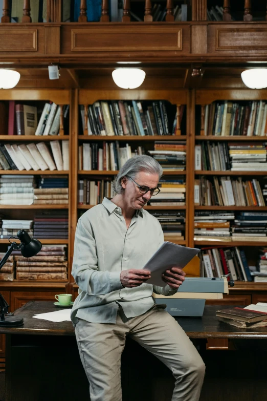 an elderly man reading a book in front of a bookshelf