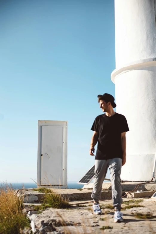 a man in jeans, black shirt and white building