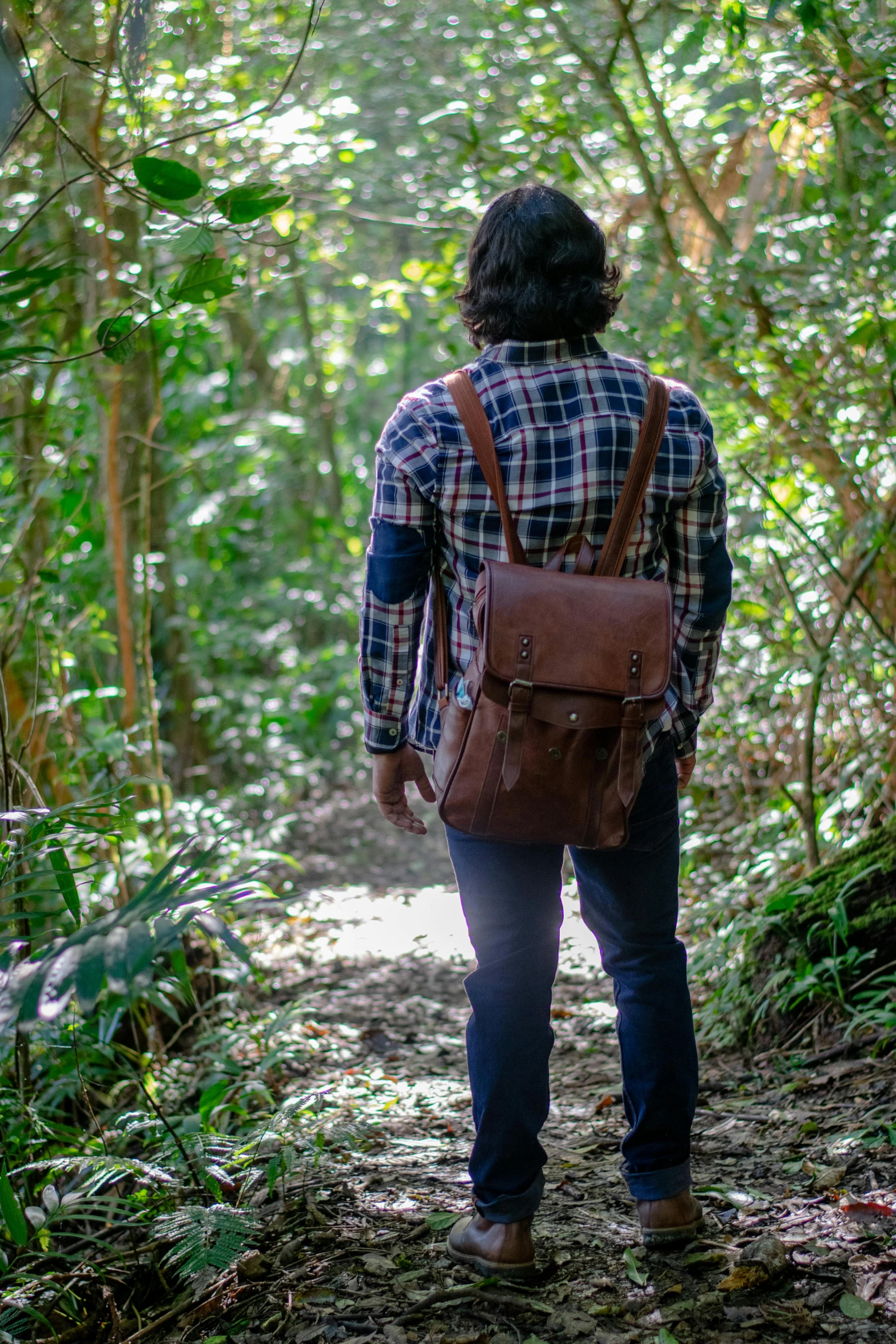 a man with a brown backpack is standing in the woods