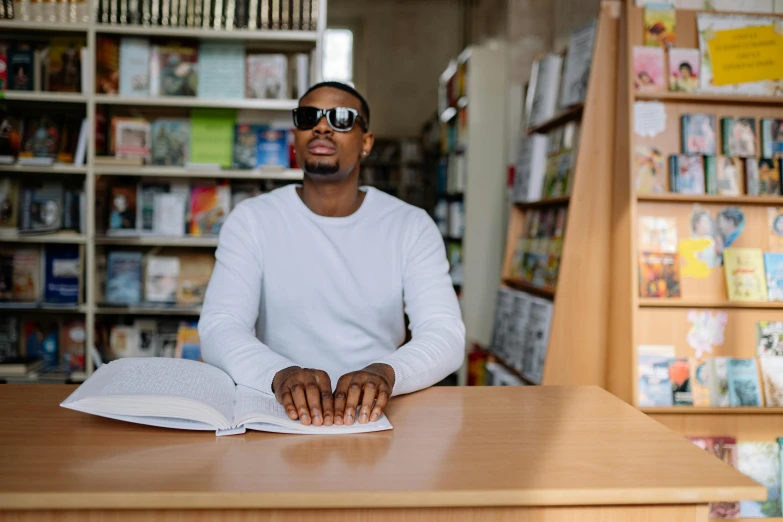 a man that is sitting at a table with a book