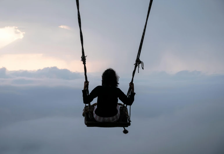 a person swinging on a cloudy day