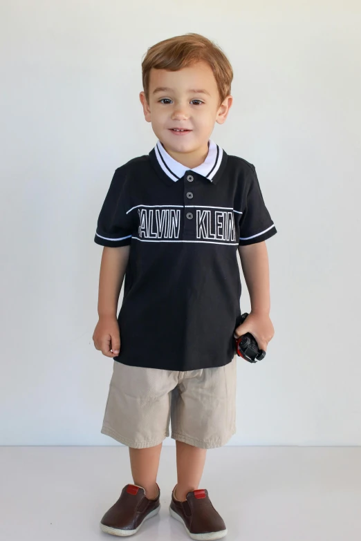 a small boy in a shirt standing against a wall