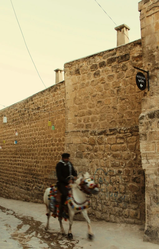 two people are riding horses near a brick wall