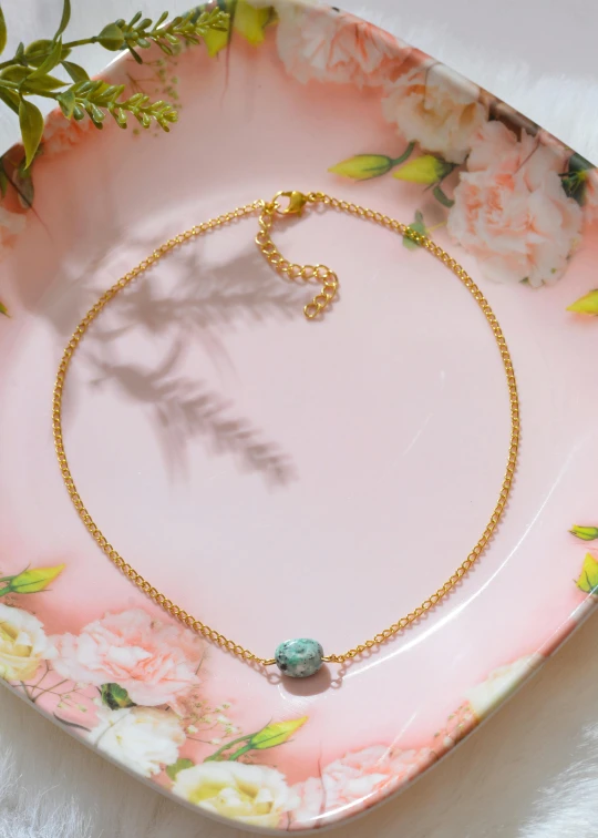 a chain necklace on a floral pink plate