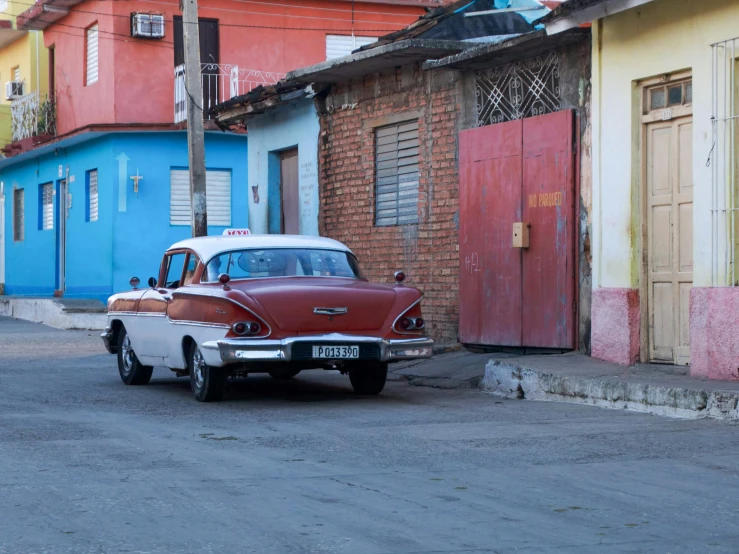 an old fashioned red car parked in front of a building