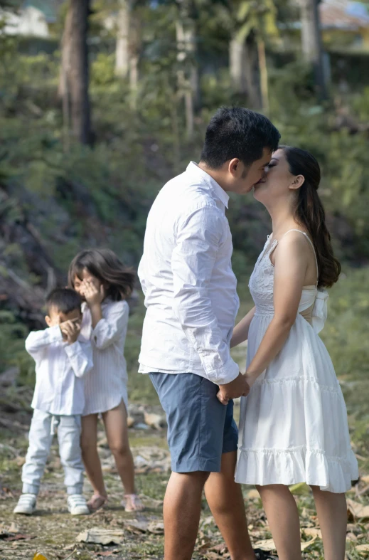 a man and woman in white kissing near other women