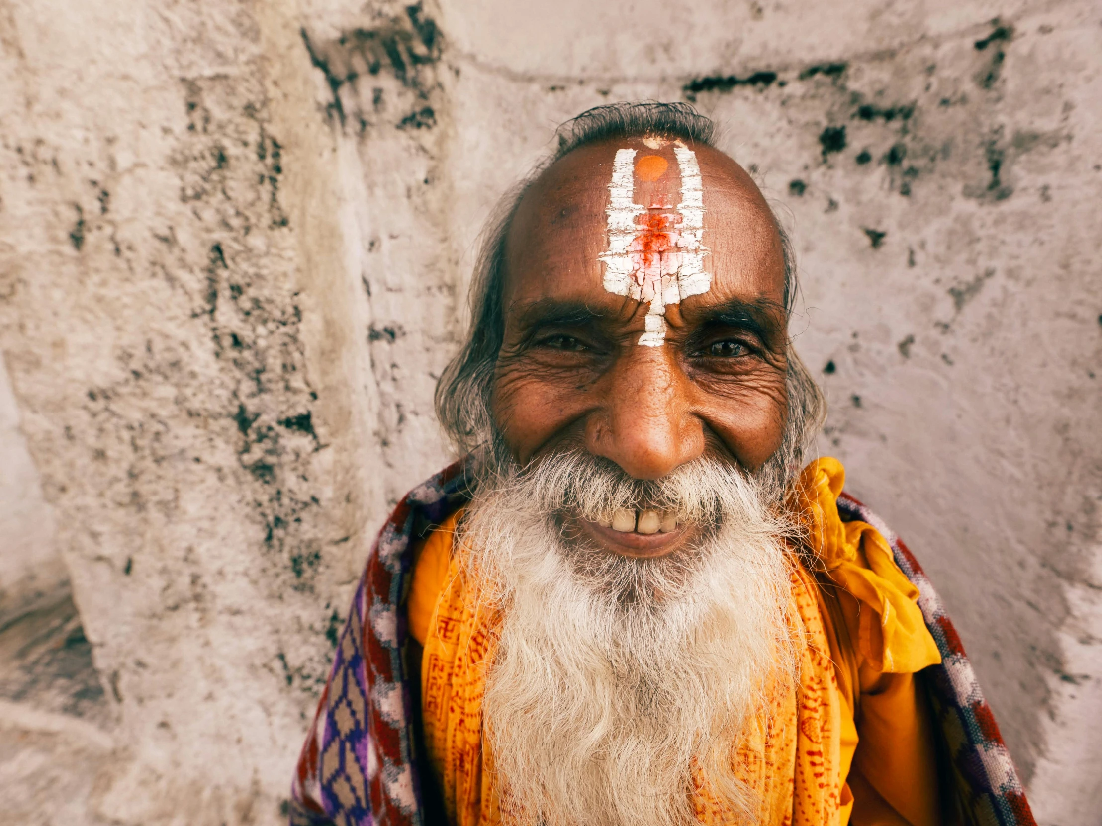 a man wearing an orange shawl with a white face