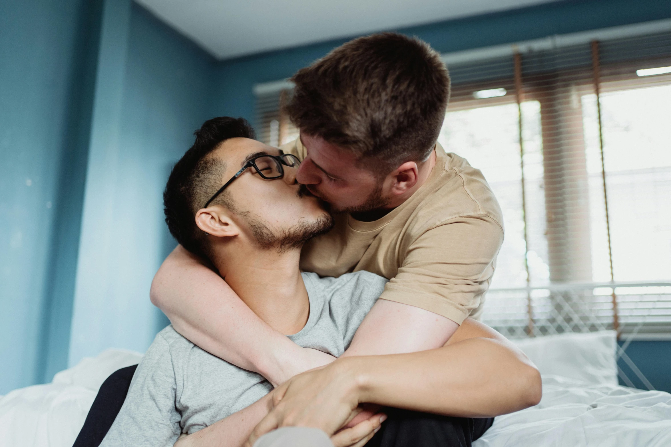 a man with glasses kissing his friend on the cheek