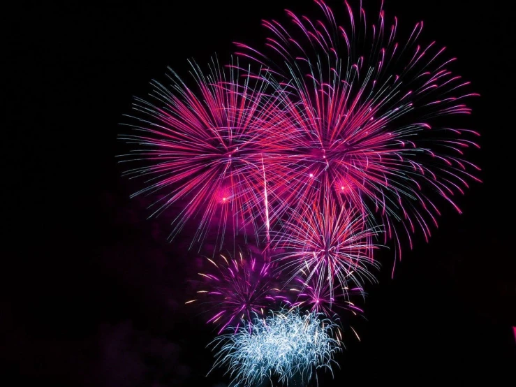 a pink and blue fireworks show is above the water