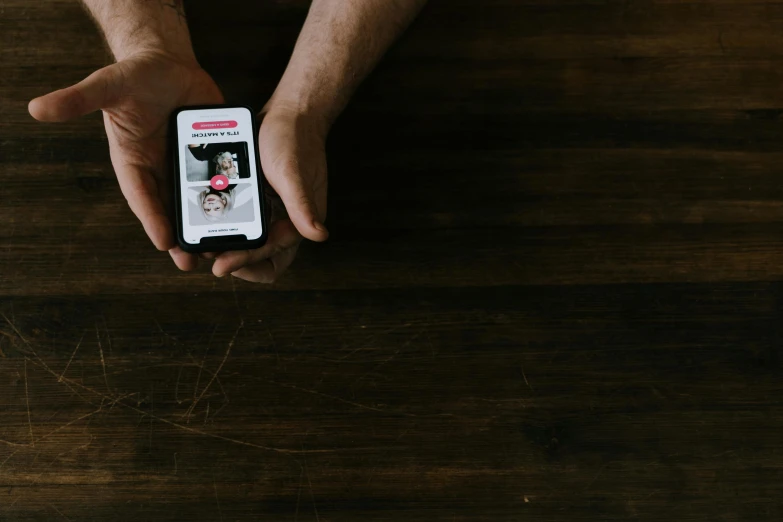 a person holding a cell phone on top of a table