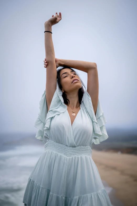 a woman in a white dress holding her arms in the air