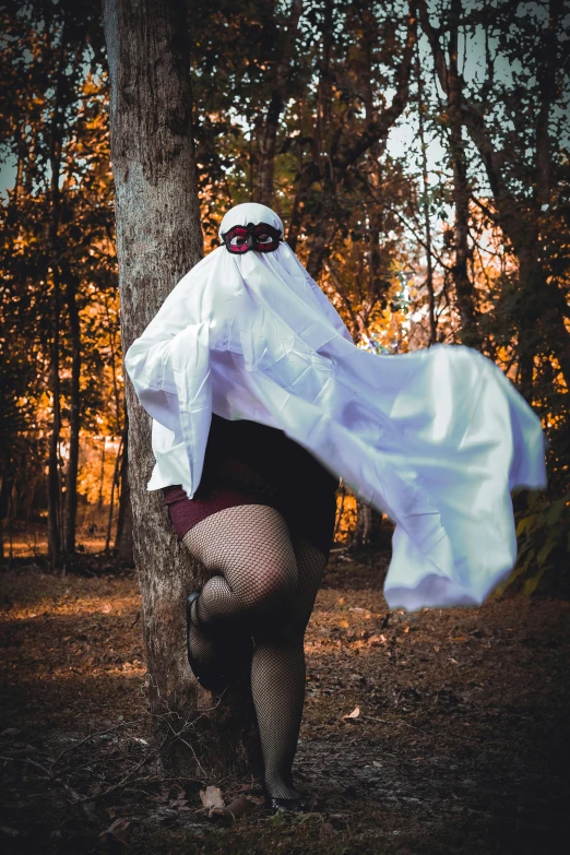 a woman in a white coat is leaning on a tree