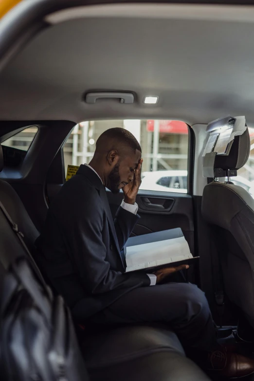 a man sitting in a car, holding papers