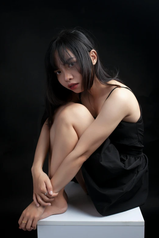 a female in black dress sitting on a stool