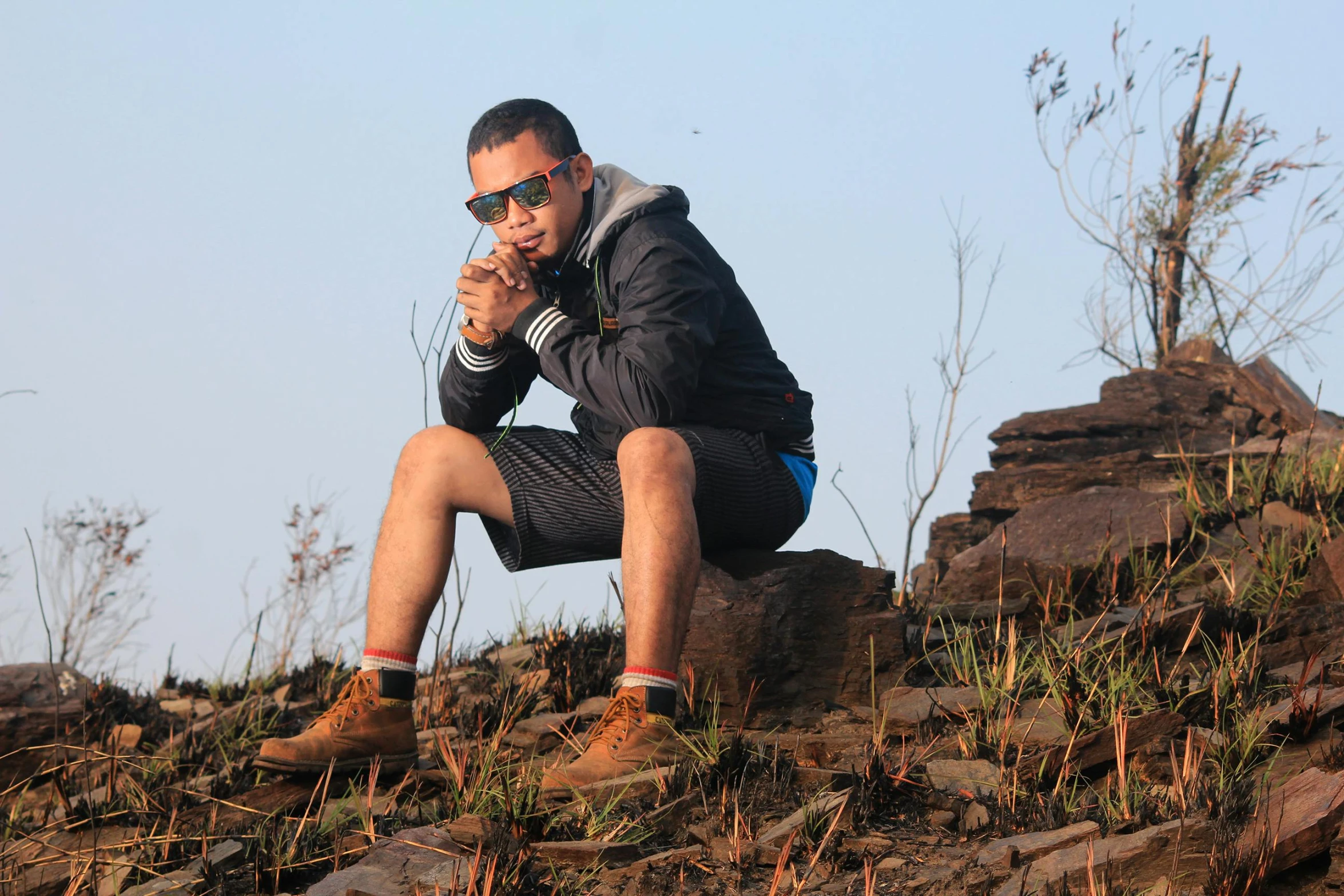 a man crouches on a rocky hillside