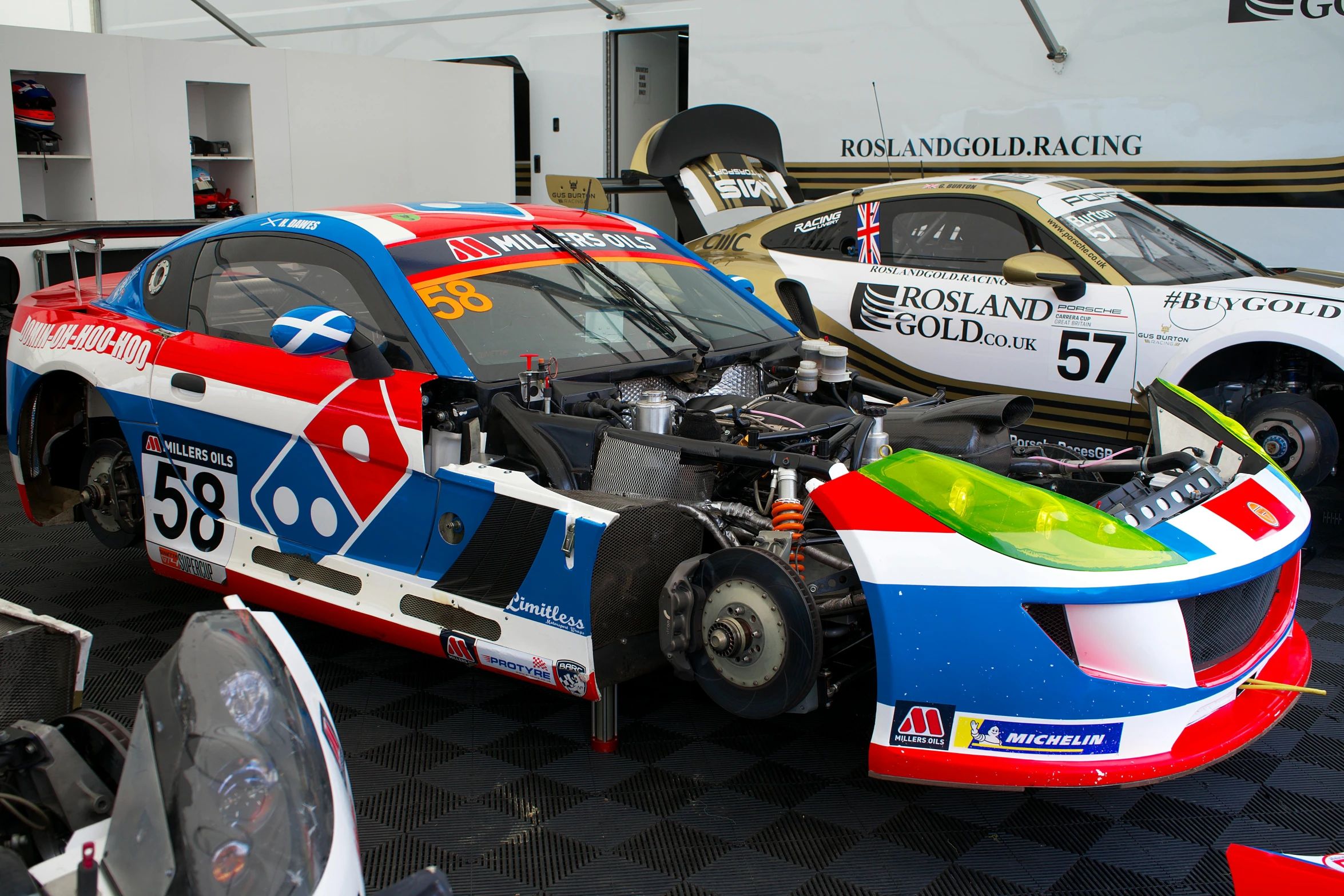 two race cars being worked on by mechanics