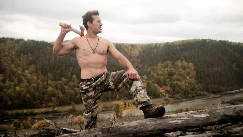 a young man playing with sticks and a log