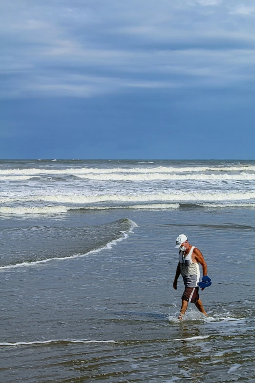 a man walks along a shore with a surfboard