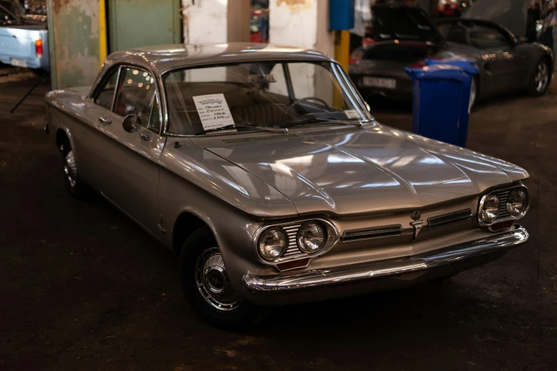 an older car sitting in a garage next to another car