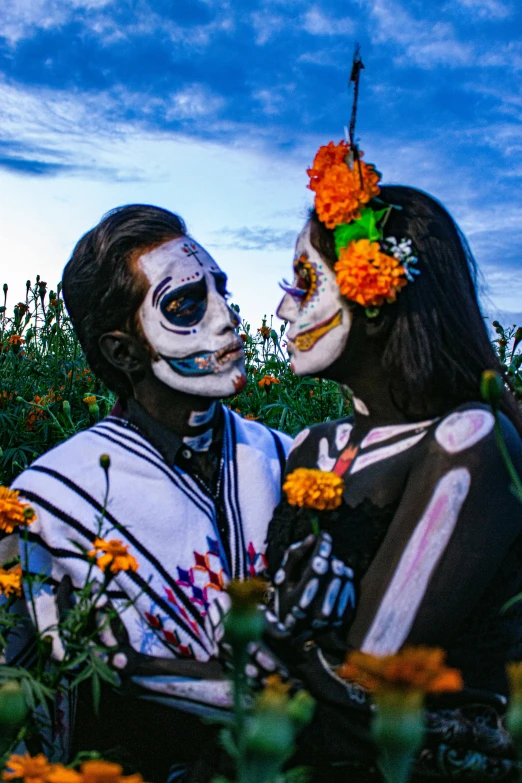 two people in day of the dead makeup kiss on the cheek