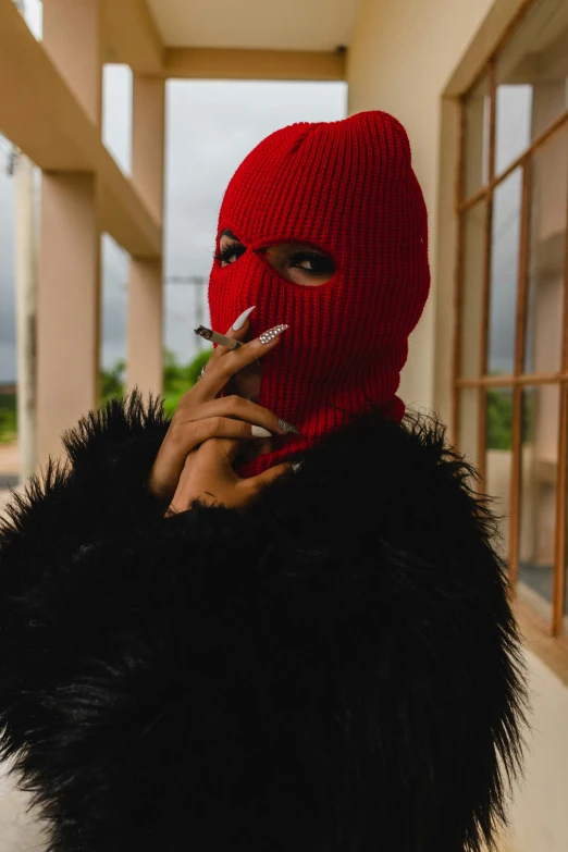 a person in a red knitted mask smoking a cigarette
