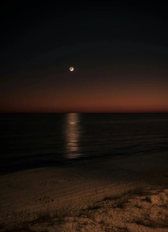a beach at night with the moon lit up