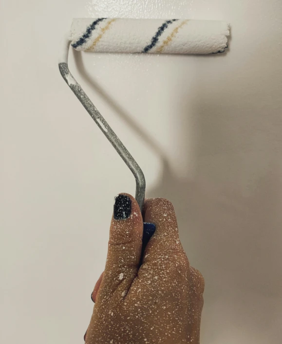 the person's hand holds a small brush with the wallpaper