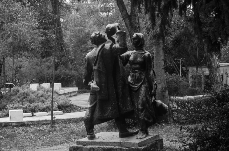 black and white image of statue at park with people standing around
