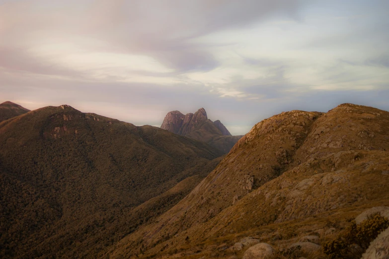 a bird flying in the air over some brown mountains