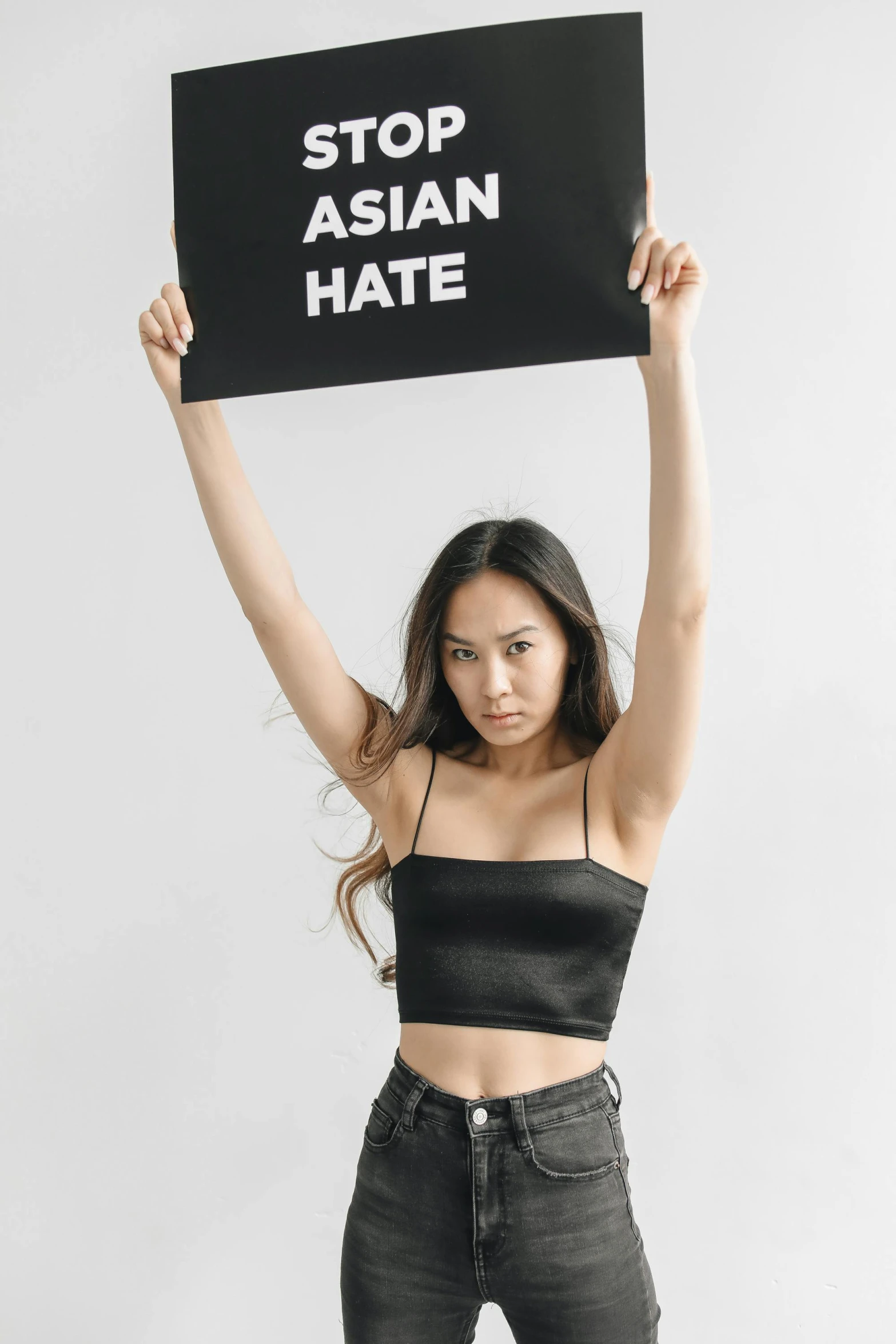a woman holding up a sign that reads stop asian hate