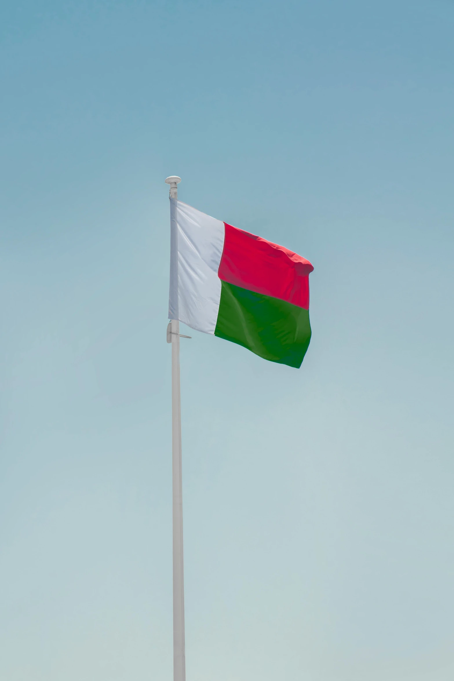 a small flag on top of a metal pole in a clear blue sky