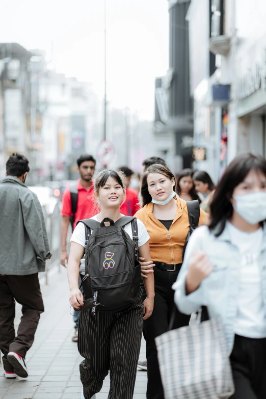 two people walking down a street near a crowd of people