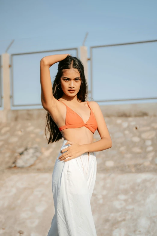 a girl is standing in the sand with her arm above her head