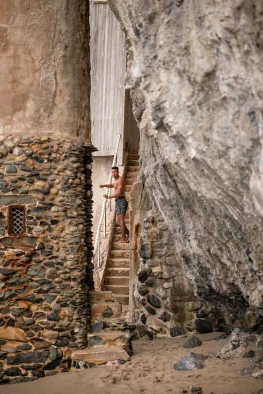 man standing on stairway between two old stone walls