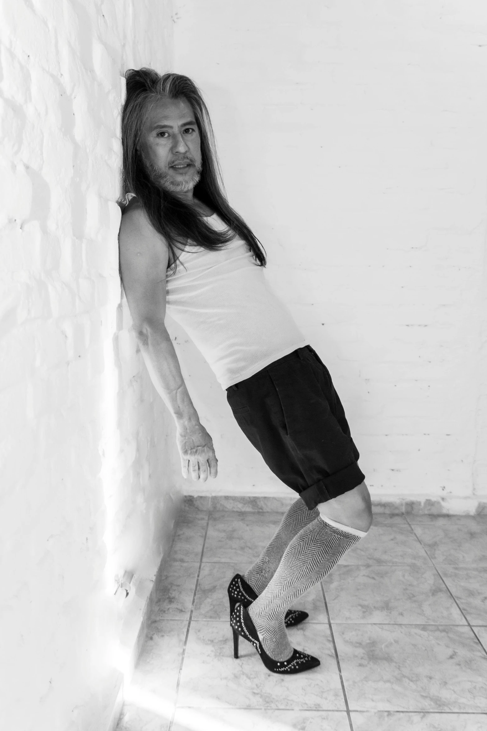 a woman is standing by a wall, posing for the camera