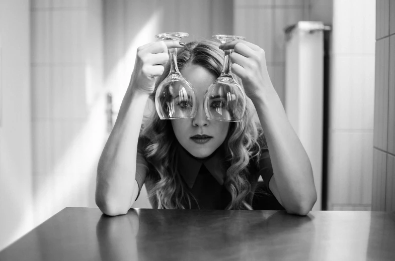 a woman holding two glasses with her fingers on top of her head